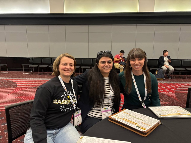 two graduate students and a faculty member are seated at a table at AERA